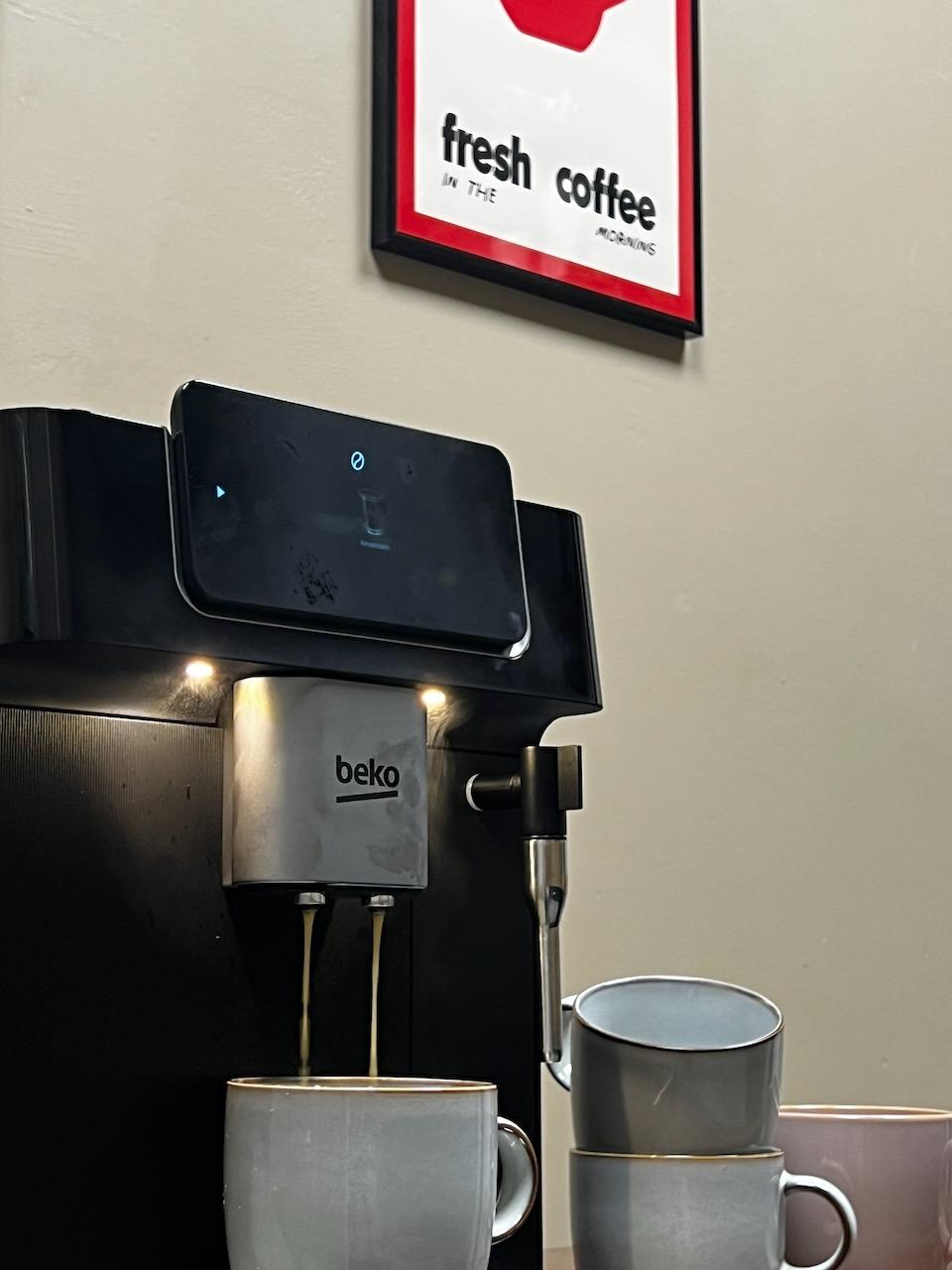The bean-to-cup coffee machine and mugs, under a fresh coffee print