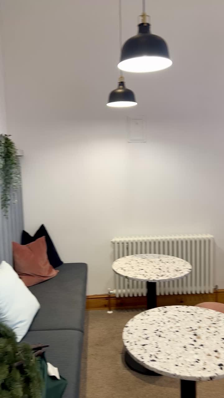 Round terrazzo tables and a sofa under black pendant lights
